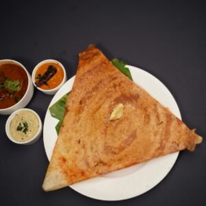 Crispy triangular dosa served with traditional chutneys and sambar on a black background.