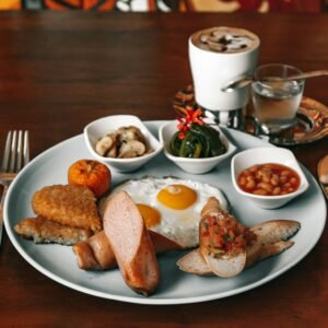 Delicious full breakfast plate with eggs, sausage, beans, and coffee on a wooden table.